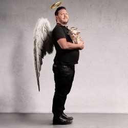 Adam Greene dressed as an angel and holding a small dog